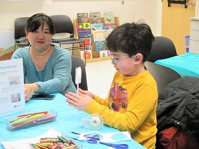 An adult and child sitting at a table and working on a craft project.